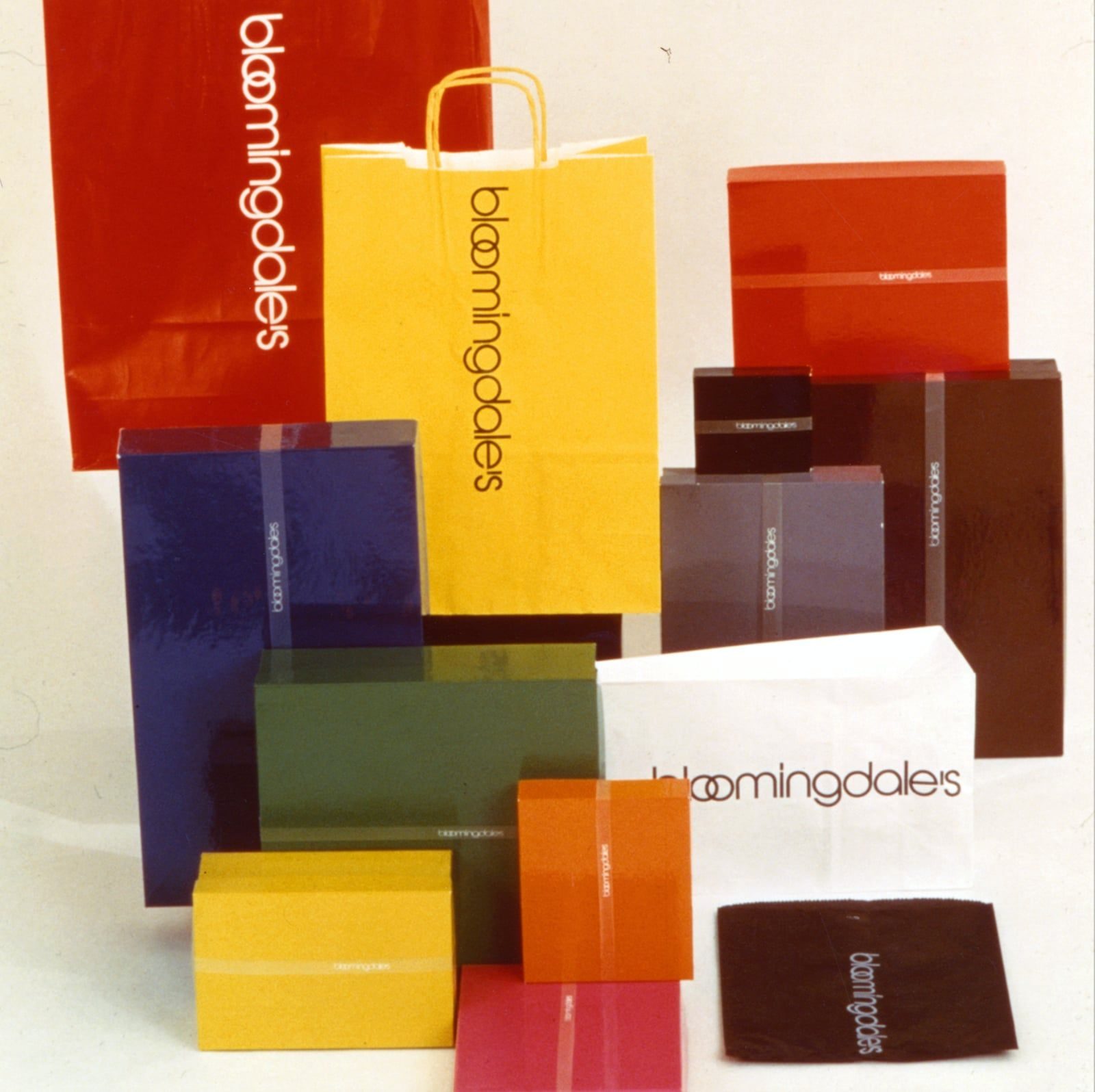 Bloomingdale's identity and packaging system by Massimo Vignelli — shopping bags and gift boxes in the house colour range, each carrying the condensed lowercase logotype
